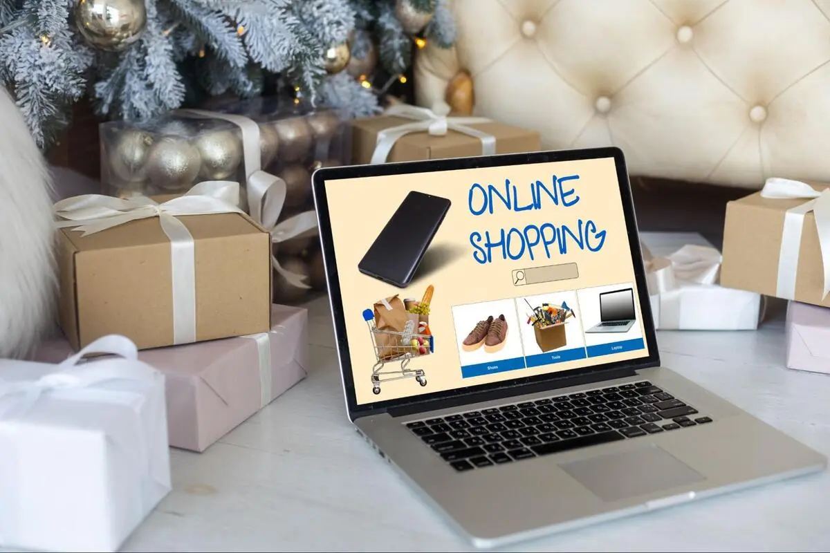 Laptop displaying an online shopping interface surrounded by wrapped gifts, illustrating consumer confidence during e-commerce promotions