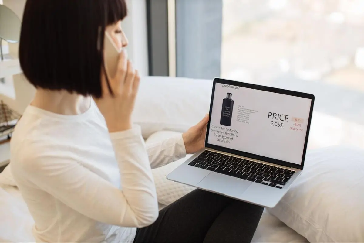 Woman viewing a laptop screen showing an e-commerce product page with price, discount percentage, and product description clearly displayed