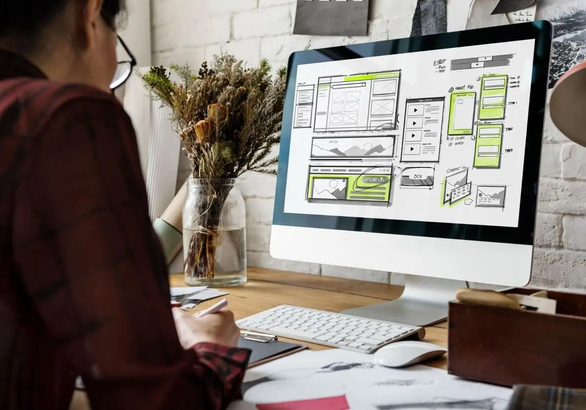 Web Designer Reviewing Website Layout Web designer reviewing wireframe layouts on a desktop screen during website development planning