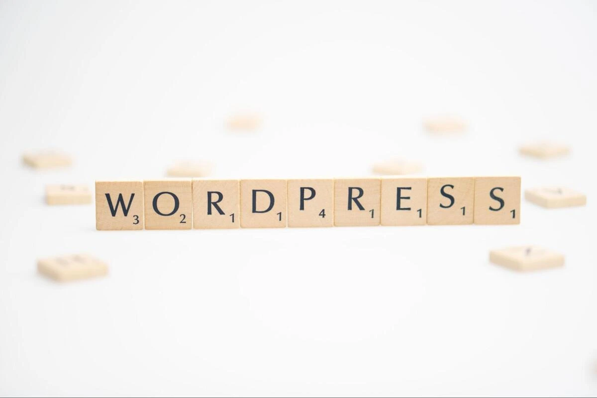 Wooden letter tiles spelling out Wooden scrabble tiles spelling out WordPress on a light neutral background.